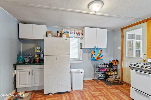 kitchen featuring white cabinets, white appliances, plenty of natural light, and light parquet flooring