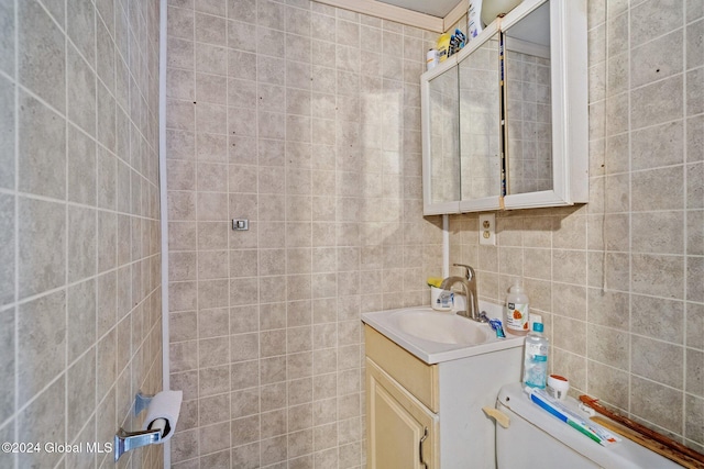 bathroom featuring vanity, crown molding, and tile walls