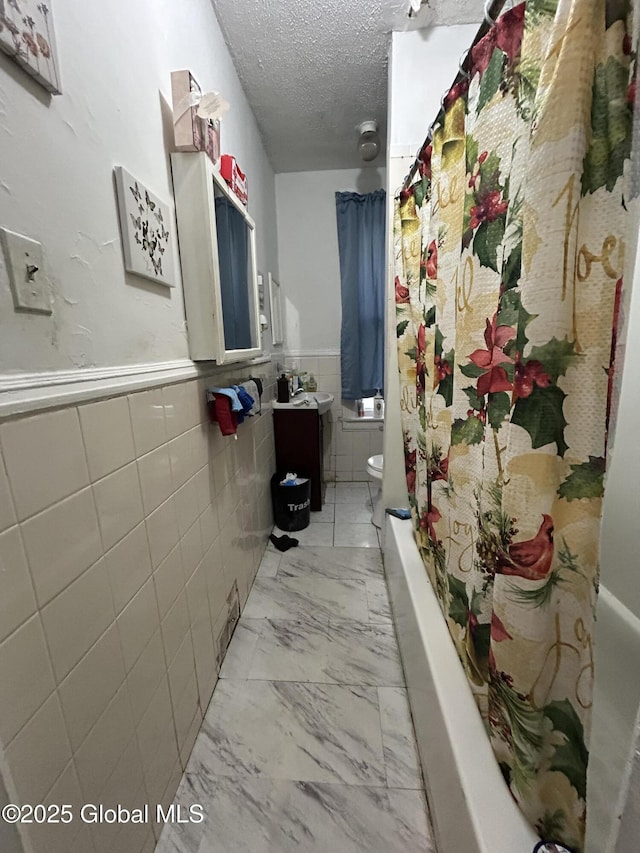 bathroom with toilet, tile walls, and a textured ceiling