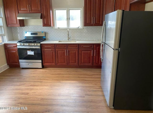 kitchen with tasteful backsplash, sink, light wood-type flooring, and appliances with stainless steel finishes