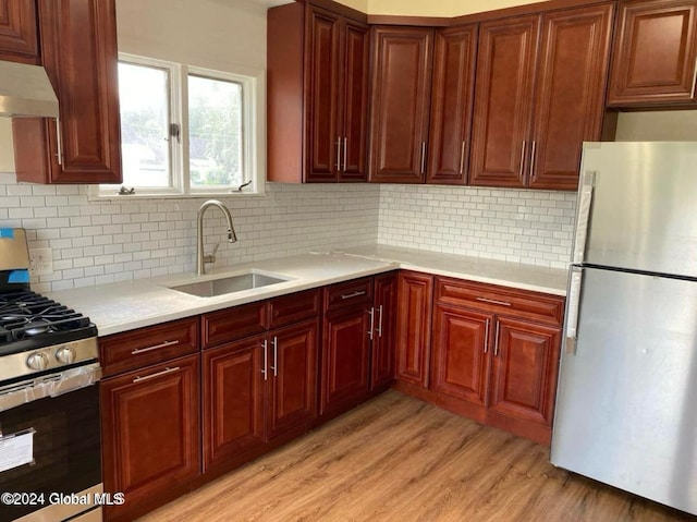 kitchen with decorative backsplash, sink, stainless steel appliances, and light hardwood / wood-style flooring