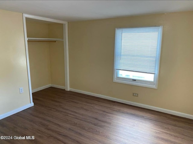 unfurnished bedroom with a closet and dark hardwood / wood-style flooring