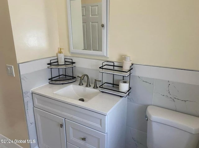 bathroom featuring vanity, toilet, and tile walls