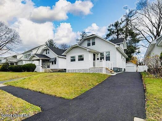 view of front of property with a garage, an outbuilding, and a front lawn