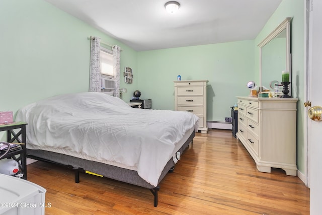 bedroom featuring light hardwood / wood-style floors and a baseboard heating unit