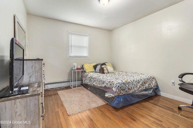 bedroom with hardwood / wood-style floors and a baseboard radiator