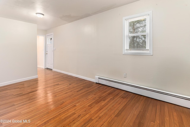 spare room with wood-type flooring and a baseboard heating unit