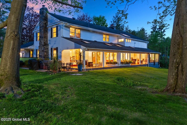 back house at dusk with a yard and a patio