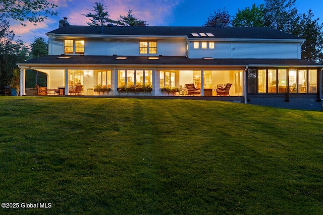 back house at dusk featuring a yard