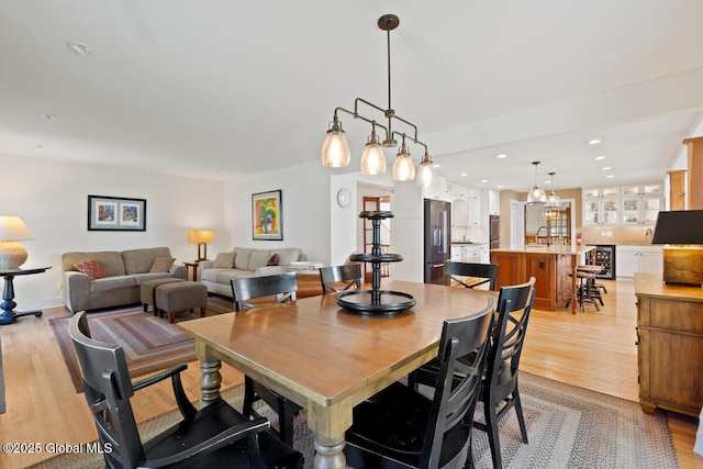 dining space featuring light hardwood / wood-style floors, beverage cooler, and sink