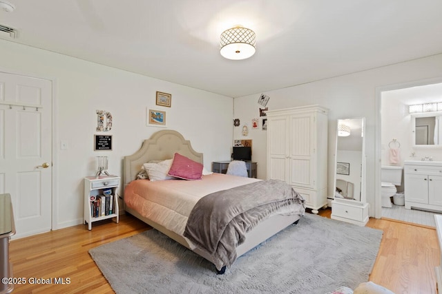 bedroom featuring sink, light hardwood / wood-style flooring, and ensuite bath