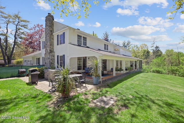 back of house with a lawn, a patio area, and a hot tub