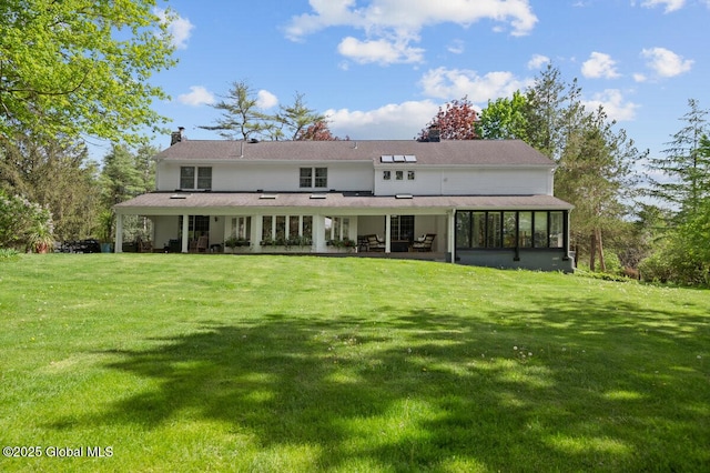 rear view of property featuring a sunroom and a yard