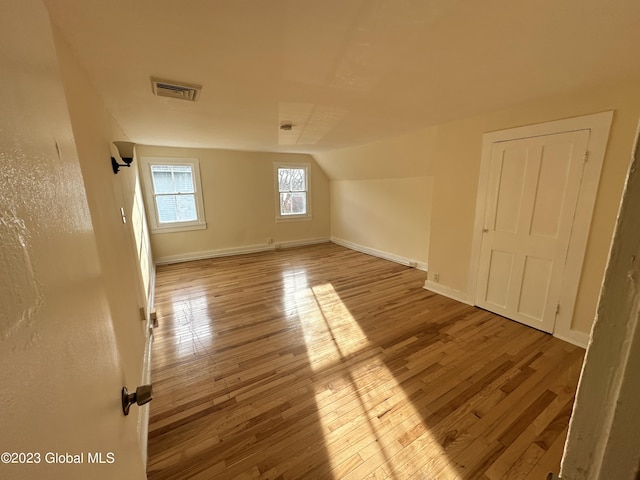 additional living space featuring light wood-type flooring and vaulted ceiling