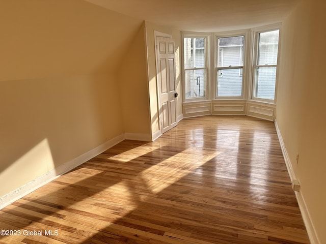 additional living space with light wood-type flooring and vaulted ceiling