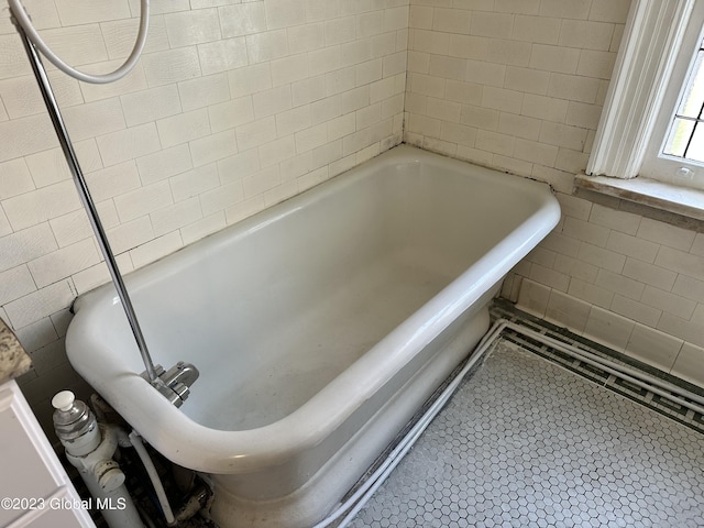 bathroom featuring tile patterned floors, a tub, and tile walls