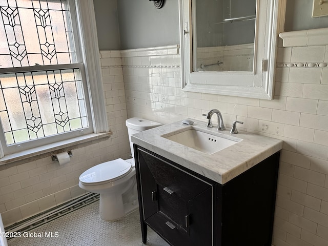 bathroom featuring tile patterned flooring, vanity, toilet, and tile walls