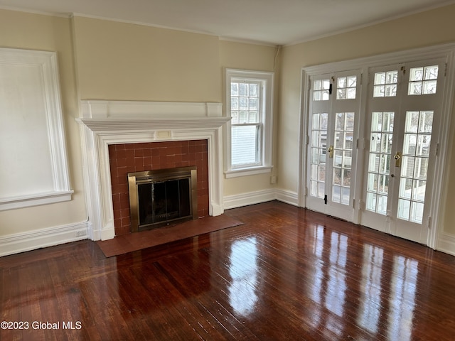 unfurnished living room with a fireplace, ornamental molding, dark wood-type flooring, and french doors