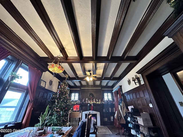 unfurnished living room featuring beamed ceiling, crown molding, ceiling fan, and coffered ceiling