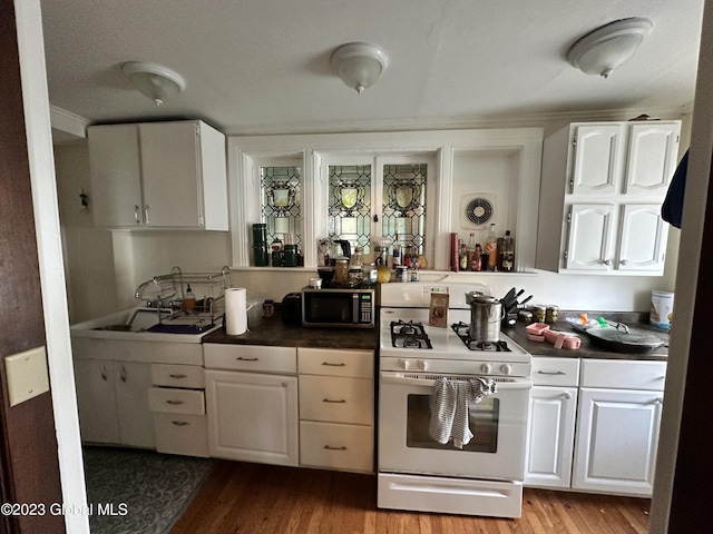 kitchen featuring white cabinets, range with gas stovetop, and light wood-type flooring