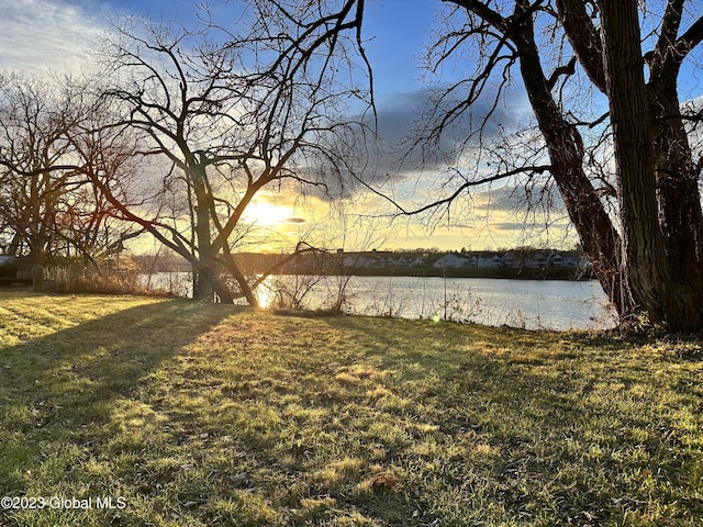 yard at dusk featuring a water view