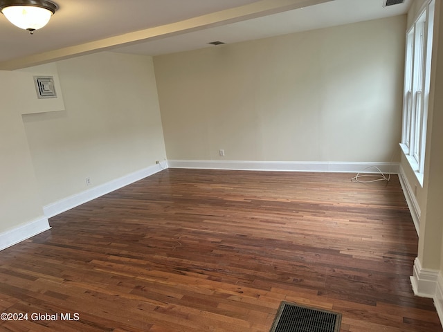 spare room featuring beam ceiling and dark hardwood / wood-style floors