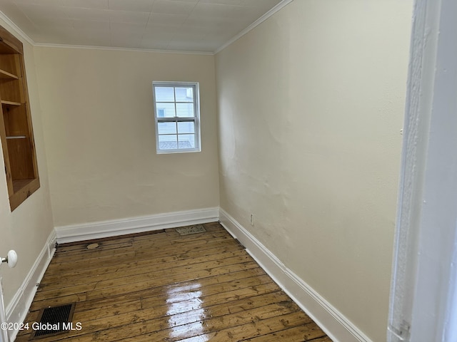 empty room with hardwood / wood-style flooring and crown molding