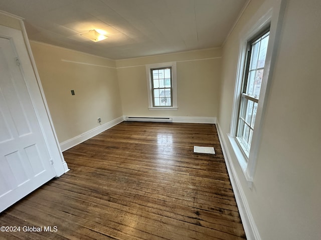 spare room with baseboard heating, dark hardwood / wood-style flooring, and ornamental molding