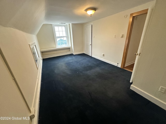 bonus room featuring vaulted ceiling and dark colored carpet