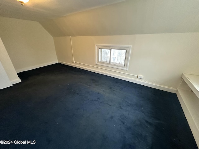 bonus room featuring dark carpet and vaulted ceiling