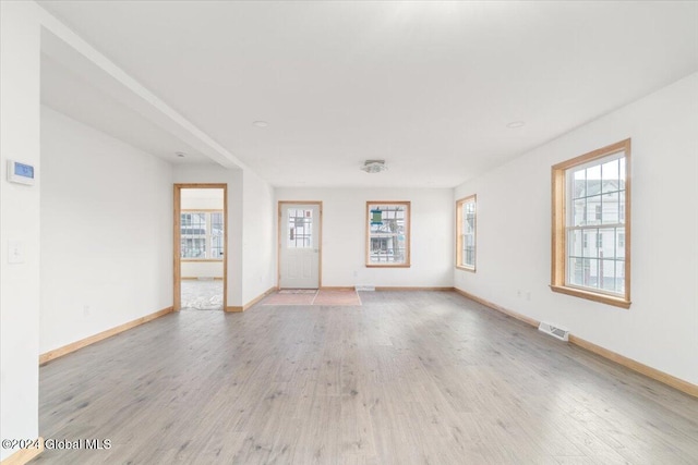 unfurnished living room with visible vents, baseboards, and light wood-style floors