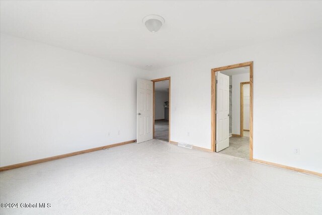 empty room featuring light carpet, visible vents, and baseboards