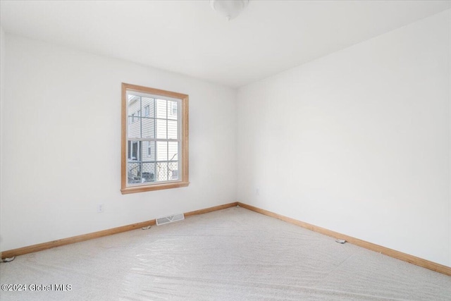 empty room with light colored carpet, visible vents, and baseboards