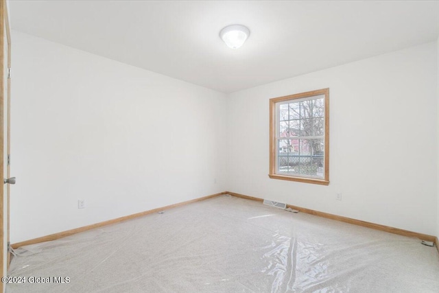 empty room featuring visible vents, light colored carpet, and baseboards