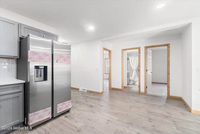 kitchen featuring visible vents, gray cabinetry, stainless steel fridge with ice dispenser, light countertops, and light wood-style flooring