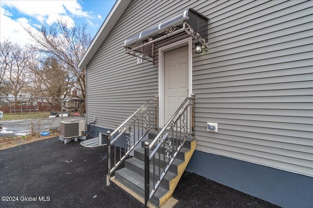 view of exterior entry with central AC unit and fence