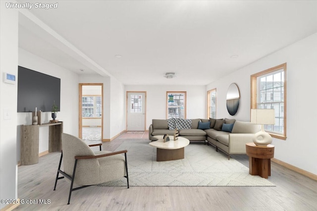 living area with a wealth of natural light, baseboards, and wood finished floors