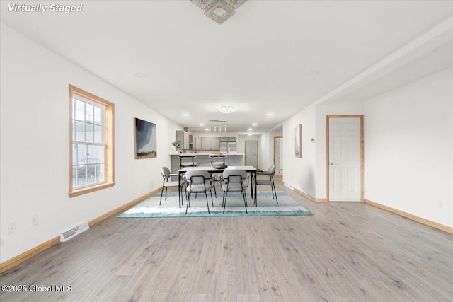 dining room with visible vents, baseboards, and light wood finished floors