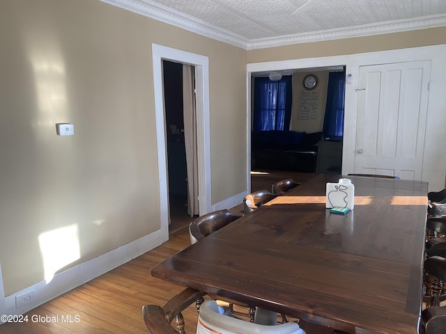 dining area with crown molding and hardwood / wood-style flooring