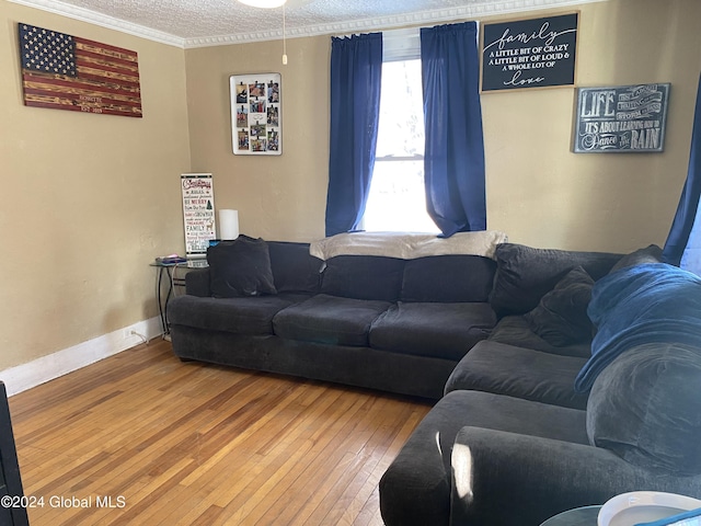 living room featuring ceiling fan, wood-type flooring, a textured ceiling, and ornamental molding