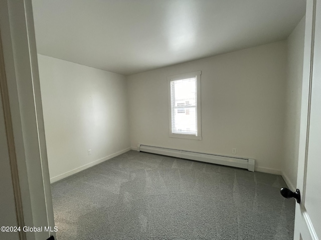 carpeted spare room featuring a baseboard heating unit