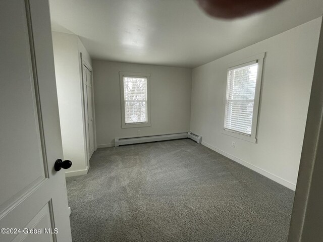 carpeted spare room featuring baseboard heating