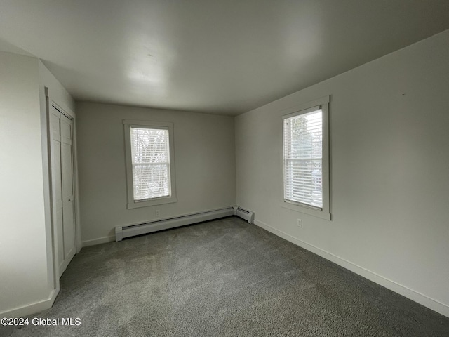 unfurnished bedroom featuring baseboard heating, multiple windows, and carpet floors