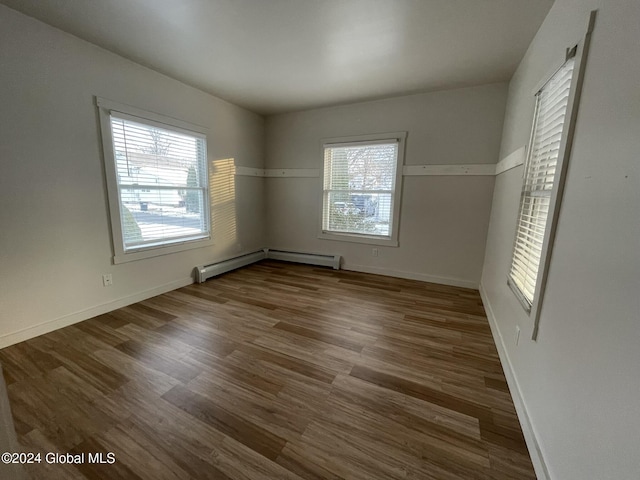 empty room with baseboard heating and dark wood-type flooring