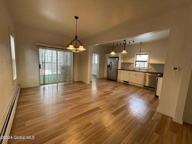 interior space with appliances with stainless steel finishes, a baseboard radiator, white cabinets, light hardwood / wood-style floors, and hanging light fixtures