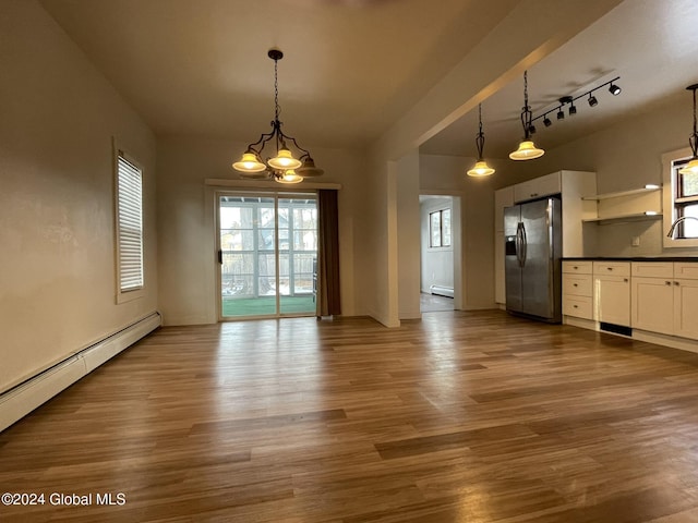 unfurnished dining area with hardwood / wood-style flooring, rail lighting, baseboard heating, and a chandelier