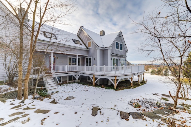 snow covered back of property featuring a wooden deck