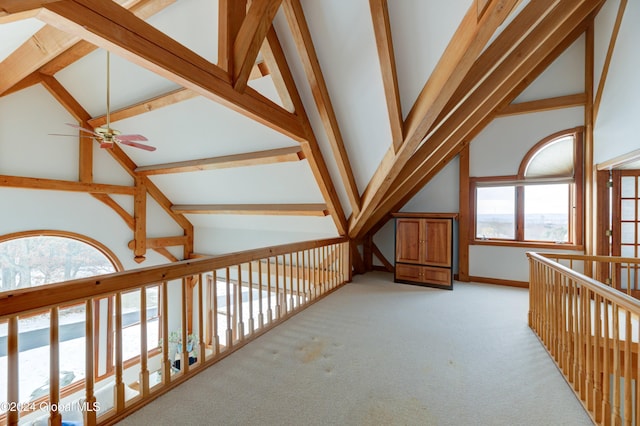 hall with beam ceiling, light carpet, and high vaulted ceiling