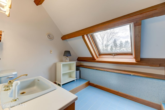 bathroom featuring tile patterned floors, lofted ceiling, and sink