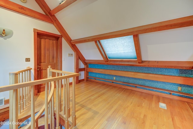 additional living space with wood-type flooring and vaulted ceiling with skylight